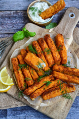Close up of   Crispy breaded  deep fried fish fingers with breadcrumbs served  with remoulade sauce and  lemon Cod Fish Nuggets on rustic wood table background