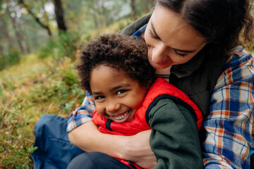 Mother embracing happy son in forest