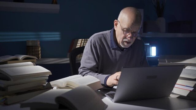 Elderly researcher or historian man reading a book, using laptop alone in dark study room.
Thoughtful elderly researcher using laptop and browsing scientific books in his office.
