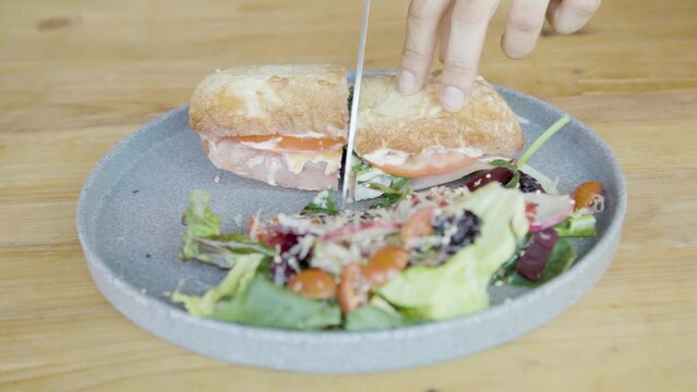 Plano a detalle de emparedado de jam&oacute;n acompa&ntilde;ado de ensalada, queso, aderezo, vegetales sobre mesa