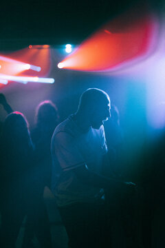 Cheerful young man dancing against illuminated spotlight at nightclub