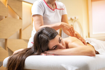 Obraz na płótnie Canvas Relaxed young woman enjoying full body massage at spa beauty salon.