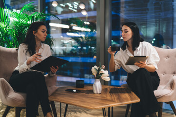 Businesswomen sitting at table with laptop and drinking coffee