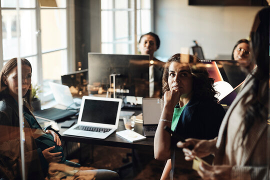 Female colleagues looking at mature entrepreneurs during business meeting in office