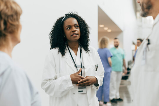 Mature female doctor discussing with colleagues at hospital