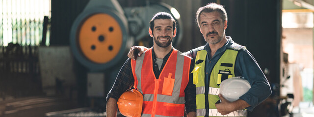 Portrait of senior and young male engineers and workers wearing safety vests and jacket while...