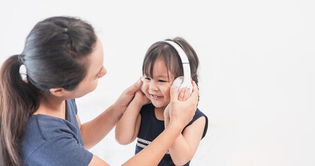 The mother put headphones on her daughter and listened to music happily.