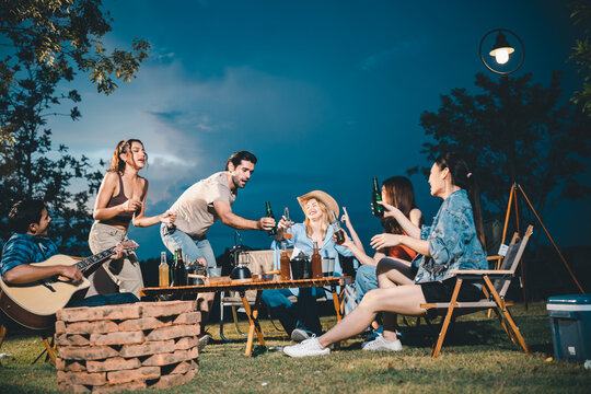 Young hipster people having fun to music dining and drinking together in campsite - Travel vacation lifestyle and youth culture concept, Happy friends group toasting beers at barbecue camping party