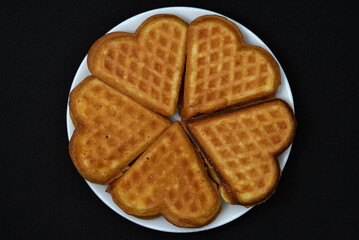 Heart-shaped waffles on a white plate. Delicious heart-shaped waffles.