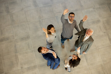 Aerial view at happy business people raise hands together with joy and success in the office hallway