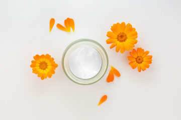 Cosmetic white container with cream and calendula,marigold flowers. Organic cosmetic concept. Flat lay,copy space.