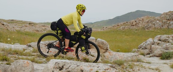 The athletic woman traveler is riding on down hill on bicycle. The beautiful picturesque valley....