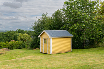 Little yellow vintage wooden house on a green field on a sunny summer day