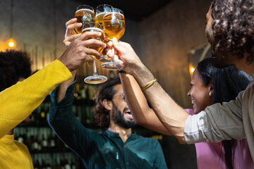 Young group of multiracial people toasting cold beer at happy hours brewery bar. After work concept