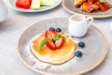 Buttermilk pancake topped with fresh berries and drizzled with maple syrup