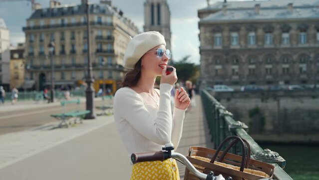 Young girl painting her lips with lipstick on the bridge
