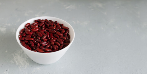 Red beans in a white bowl on a gray background. The concept of vegetarian food. Horizontal orientation. Copy space.