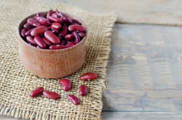 Red beans in a wooden bowl on a natural background. The concept of vegan food. Rustic style. Horizontal orientation. Copy space.