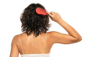 Back view head shot of woman combing her curly dark wavy  hair against white background