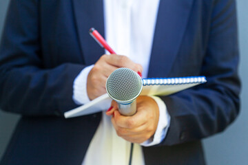 Journalist or reporter at media event, writing fake news, holding microphone