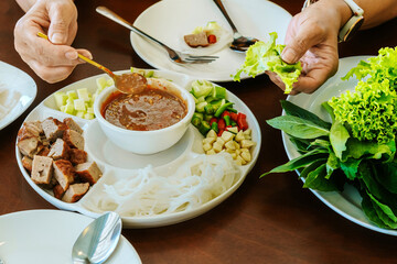 Close up to dipping sauce for Vietnamese Meatball Wraps (Nam-Neung), Pork Sausage wraps with fresh vegetables in rice paper, generous platter eat with sweet sauce. Vietnamese Pork Sausage and salad.