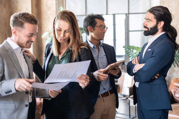 A business team huddles together, analyzing data from their latest meeting. Focused and determined, they work collaboratively to find solutions and make informed decisions. 