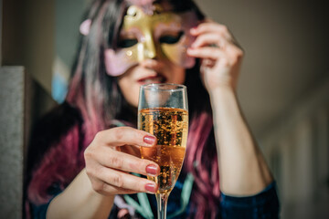 funny woman with party mask with glass of champagne