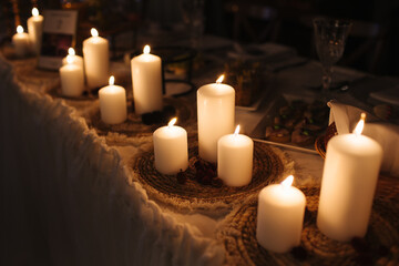 Boho wedding decoration. Rustic decorations of wedding venue. Romantic atmosphere. White candles on a table. Vintage style interior. Wedding party in a barn.