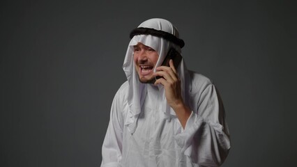 Authentic muslim businessman in traditional white kandura with beard using smartphone. Successful Saudi, Emirati, arab businessman concept.