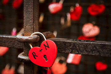padlocks in the shape of a red heart attached to the railings to express the love between two...