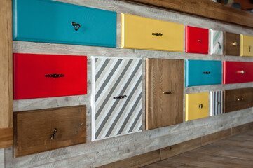 Colorful decorative drawers with handles are attached to the wall