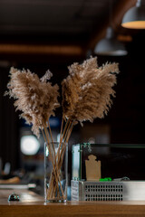 A decorative dry branch in a glass vase stands on a beauty table