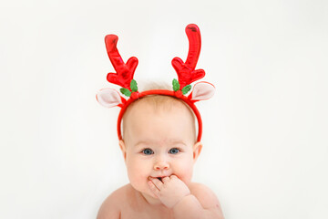 Portrait of a little baby with reindeer Christmas horns on a white background.
