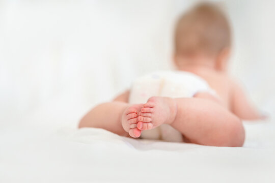 Feet of a little Caucasian baby in a diaper on a white background