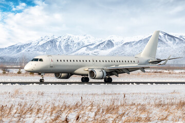 White passenger airplane on the runway of a winter airport on the background of high picturesque mountains