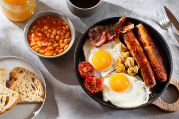 Full English breakfast with fried eggs, sausages, beans, bacon, grilled tomatoes, mushrooms, toasts...