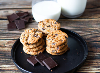 Chocolate cookies with pieces of chocolate on a wooden background