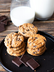 Chocolate cookies with pieces of chocolate on a wooden background