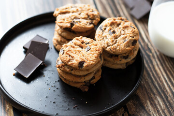 Chocolate cookies with pieces of chocolate on a wooden background