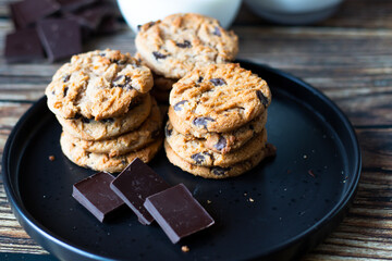 Chocolate cookies with pieces of chocolate on a wooden background