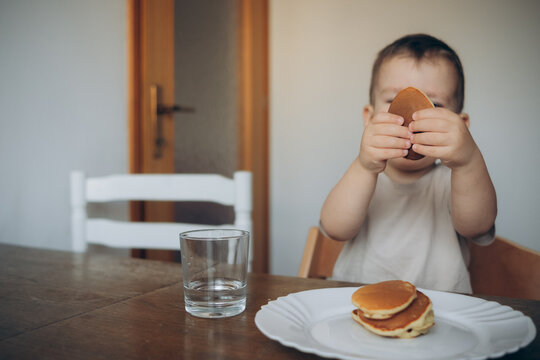 
Happy Little Boy Eating Pancakes. Portrait Of Small Cute Little Boy Child Sitting By The Table At Home Eating Pancakes.