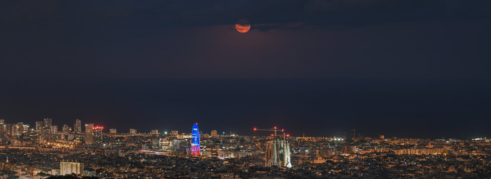 Panoramic image of he full moon rises in the city of Barcelona, Spain
