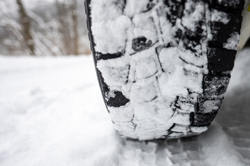 Close-up of a winter tire tread on a snow-covered road.