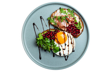 Sandwiches with jamon and fried egg on a plate decorated with herbs and sprinkled with pomegranate...