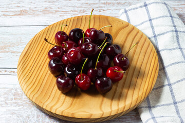 Sweet and ripe cherries on a wooden plate.