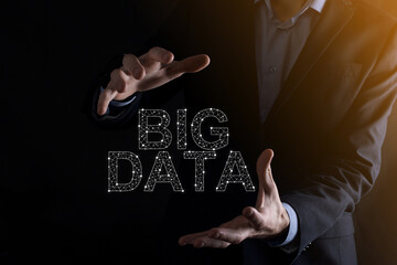 Businessman in a suit on a dark background holds the inscription BIG DATA. Storage Network Online Server Concept.Social network or business analytics representation