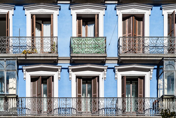 Old colorful residential building in central Madrid with iron balconies and blue stucco facade