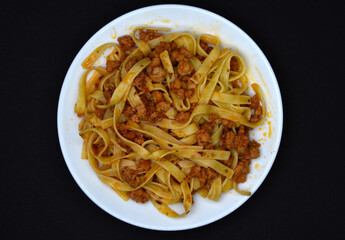 Italian pasta on a white plate. Meat and pasta with tomatoes.