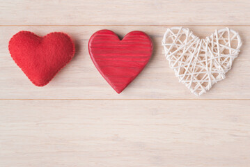 Three different decorative Valentines hearts on light wooden background with copy space. Valentine’s Day greeting card template