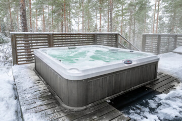 A modern outdoor hot tub embedded into the terrace on a cold winter's day.